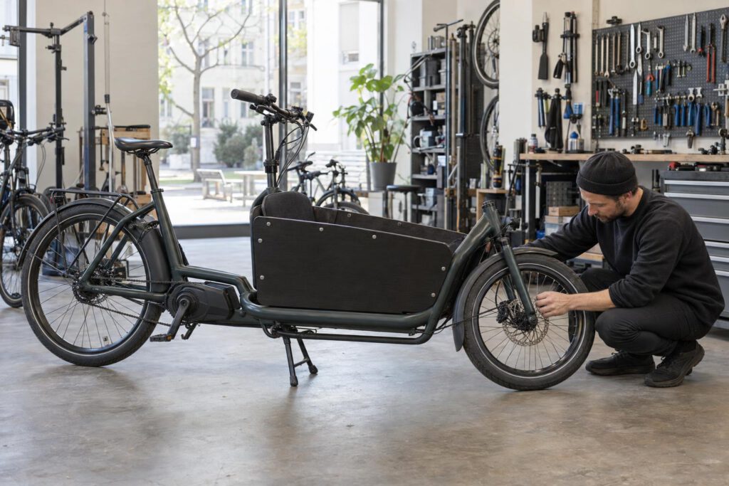 Mechaniker prüft ein gebrauchtes E-Lastenrad in der Werkstatt